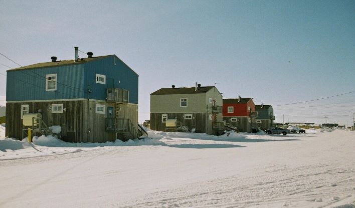 Série de maisons le long d'une rue enneigée.