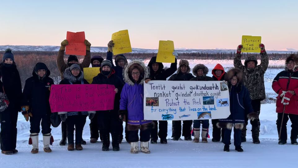 Une quinzaine de personnes dehors à Fort McPherson avec des affiches, le 21 novembre 2024.
