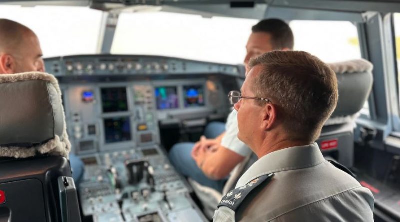 Trois hommes de forces aériennes de dos, dans le cockpit d'un avion.