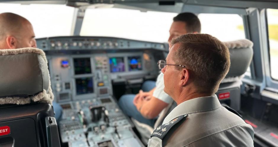Trois hommes de forces aériennes de dos, dans le cockpit d'un avion.