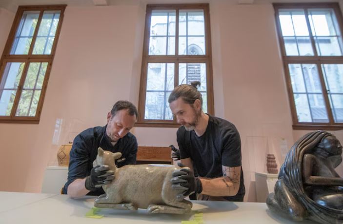 Deux hommes s'affairent à installer une sculpture.