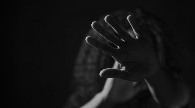 Une femme se cache le visage avec sa main.