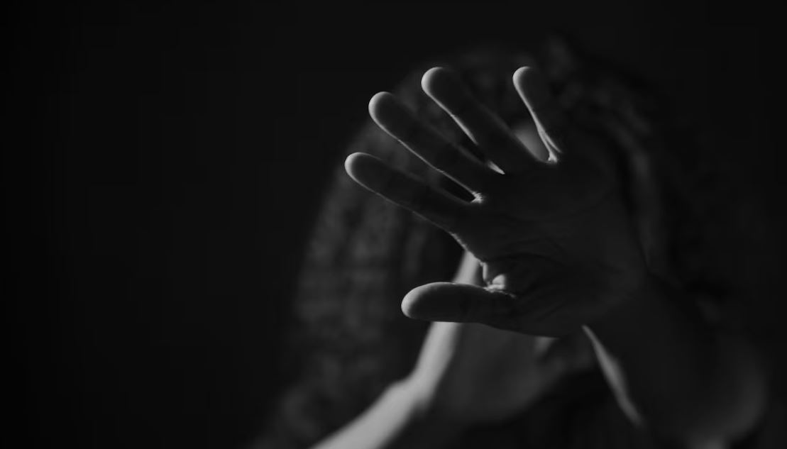 Une femme se cache le visage avec sa main.