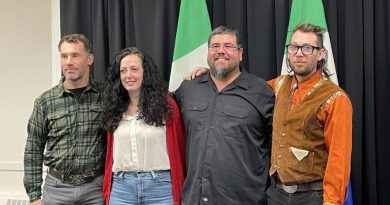 Quatre conseillers municipaux devant des drapeaux du Yukon.