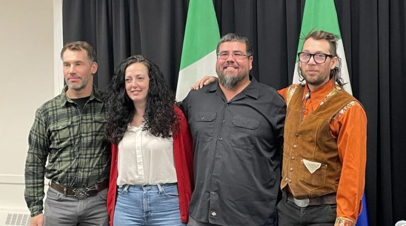 Quatre conseillers municipaux devant des drapeaux du Yukon.