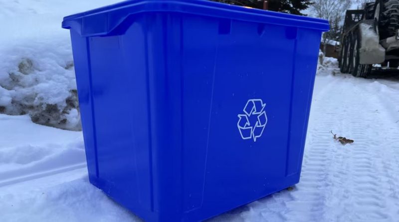 Un bac de recyclage bleu dans la neige.