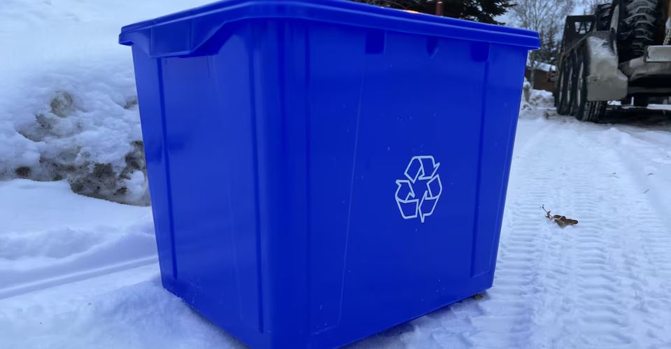 Un bac de recyclage bleu dans la neige.