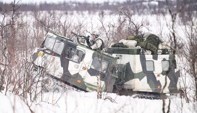 Des soldats suédois dans un char blindé camouflé entre la neige et les arbres morts.