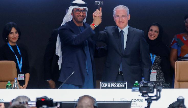 Deux hommes souriants tiennent un marteau ensemble.