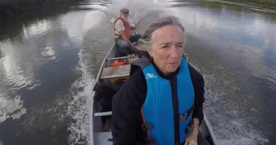 Une femme est à l'avant d'une pirogue, alors qu'un homme est à la barre.