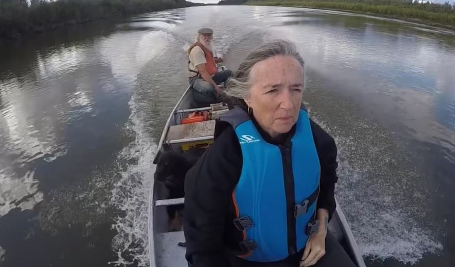 Une femme est à l'avant d'une pirogue, alors qu'un homme est à la barre.