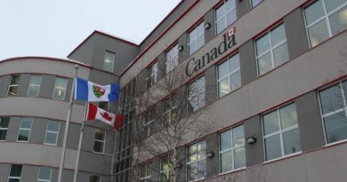 Édifice devant lequel flotte le drapeau des Territoires du Nord-Ouest et le drapeau du Canada, et sur lequel est écrit Canada, le 17 janvier 2025, à Yellowknife.