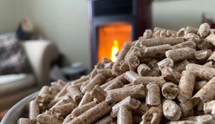 Des granulés de bois devant un poêle à bois dans un salon.