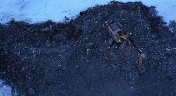 Vue aérienne sur un engin de chantier qui creuse la terre brûlée.