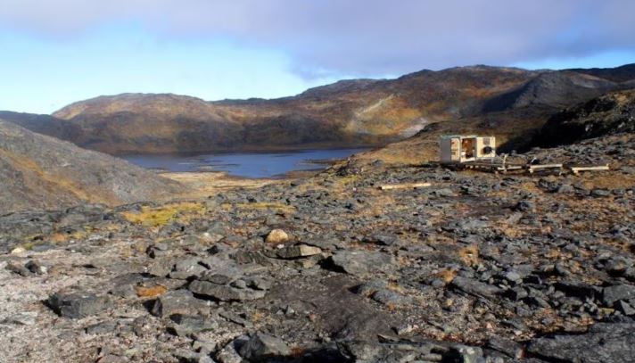 Un paysage rocheux parsemé d'équipement industriel près d'une étendue d'eau.
