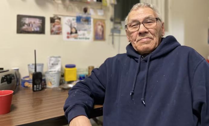 Un homme assis dans un bureau fixe une caméra du regard.