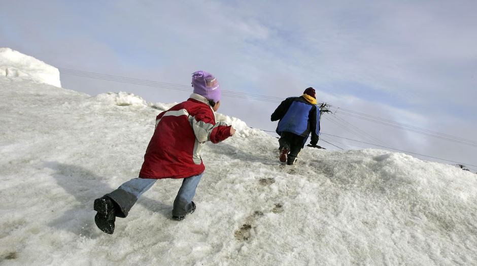 Deux enfants escaladent une montagne de neige à Browerville, en Alaska, le 7 juin 2006.