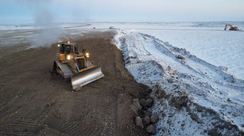 Un pelletier déblayant la neige et la terre du site du projet.