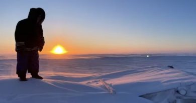 Une photo montrant un personne se tenant au sommet d'une hutte de terre recouverte d'une épaisse couche de neige, le 18 janvier 2025, au Nunavut.