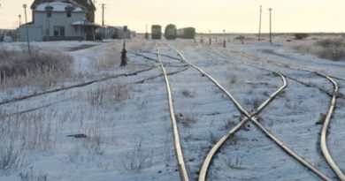 Des chemins de fer entourés de neige et des wagons au loin dans la ville de Churchill au Manitoba