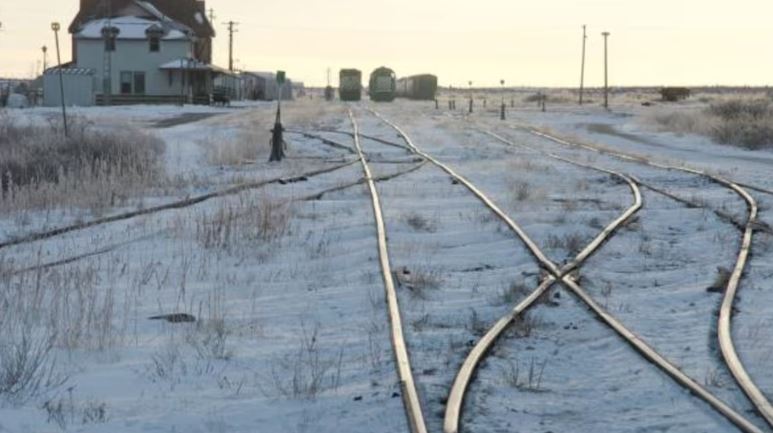 Des chemins de fer entourés de neige et des wagons au loin dans la ville de Churchill au Manitoba