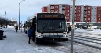 Une personne monte dans un autobus, et la neige recouvre les trottoirs.