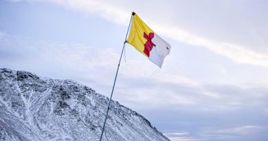 Un drapeau du Nunavut flotte dans le vent devant une montagne enneigée.