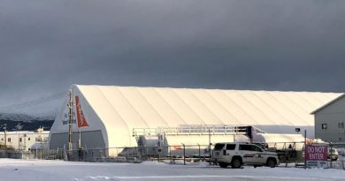 Un véhicule de police est stationné près d'une entrée qui mène vers des hangars d'avion.