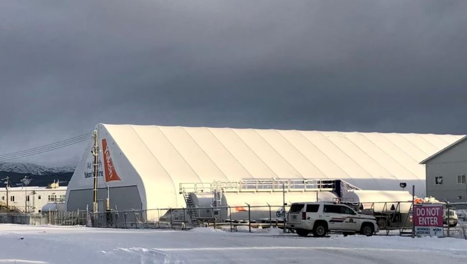 Un véhicule de police est stationné près d'une entrée qui mène vers des hangars d'avion.