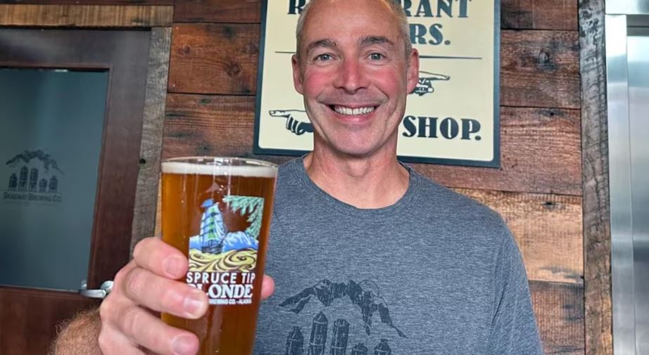 Mike Healy tenant une bière avec le sourire.