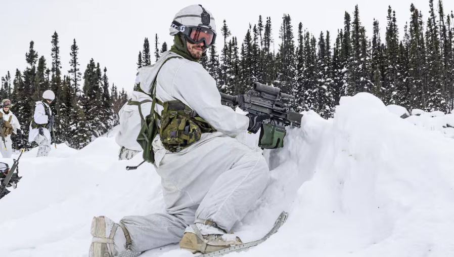 Un soldat, vêtu de blanc, porte des raquettes et des lunettes de ski.