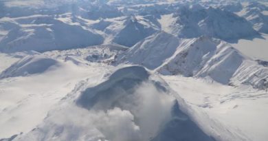 De la fumée blanchâtre s'échappe d'un cratère enneigé.
