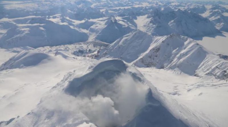 De la fumée blanchâtre s'échappe d'un cratère enneigé.