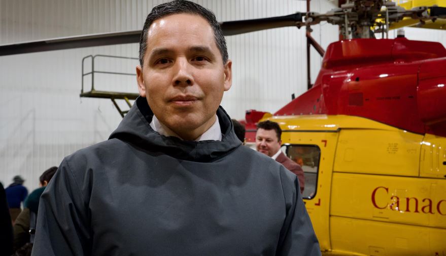 Le président de l'organisme national Inuit Tapiriit Kanatami, Natan Obed, se tient devant un hélicoptère dans un hanger des forces armées canadiennes à Iqaluit, au Nunavut, le 18 mars 2025.