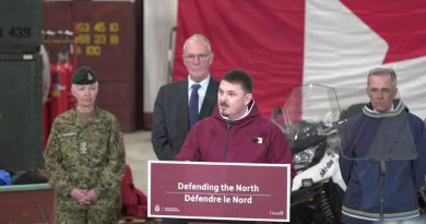 Le premier ministre du Nunavut (en rouge) parle dans un micro aux côtés du premier ministre du Canada, Mark Carney, du ministre de la Défense nationale, Bill Blair ainsi que de Jennie Carignan, chef d’état-major de la Défense, lors d'une conférence de presse à Iqaluit, au Nunavut, le 19 mars 2025.