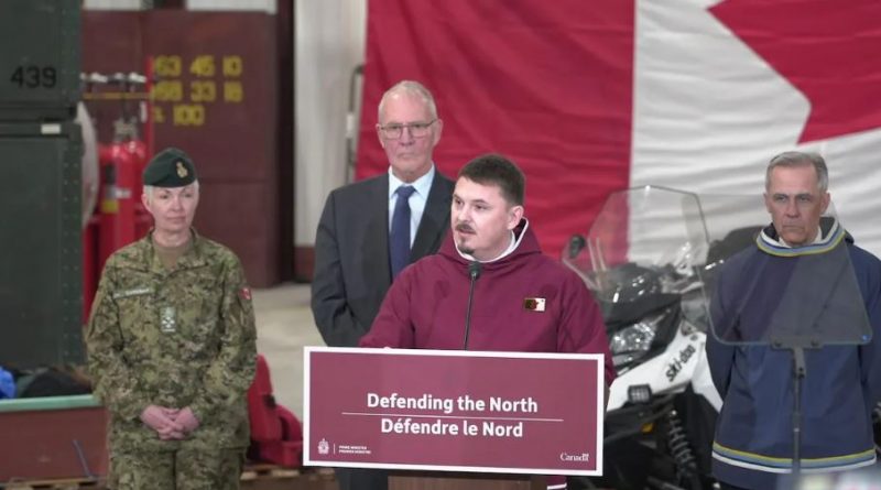 Le premier ministre du Nunavut (en rouge) parle dans un micro aux côtés du premier ministre du Canada, Mark Carney, du ministre de la Défense nationale, Bill Blair ainsi que de Jennie Carignan, chef d’état-major de la Défense, lors d'une conférence de presse à Iqaluit, au Nunavut, le 19 mars 2025.