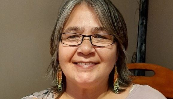 Une femme regarde la caméra en souriant.
