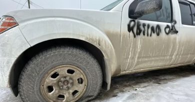 Le côté avant gauche de la voiture avec le pneu crevé et le message «démissionne ou meurt» sur la portière.