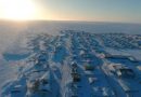 La communauté d'Arviat sous la neige photographiée de haut en avril par un drone avec le soleil à l'horizon.