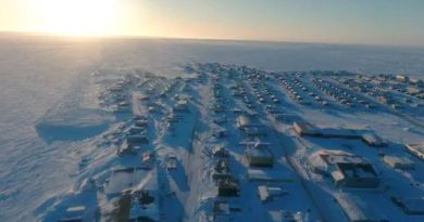 La communauté d'Arviat sous la neige photographiée de haut en avril par un drone avec le soleil à l'horizon.