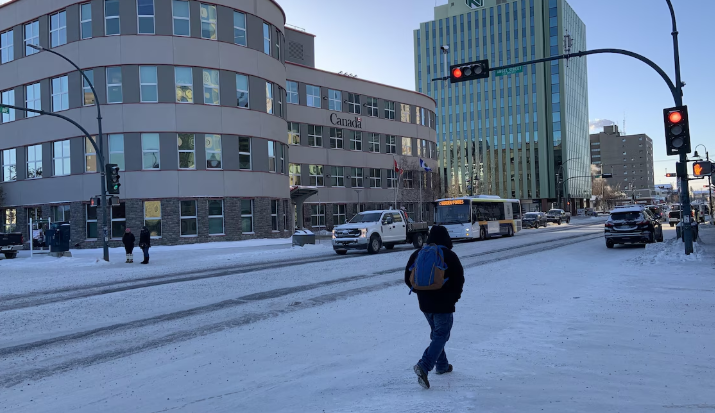 Un piéton traverse une rue enneigée au centre-ville de Yellowknife