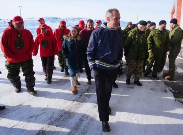 Le premier ministre Mark Carney avec une dizaine de personnes, dont des militaires, derrière lui.