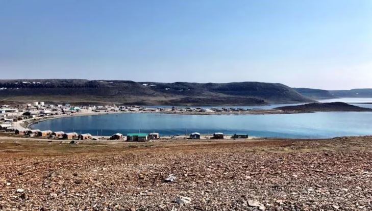 Maisons situées le long de la rive de l'océan Arctique, avec montagnes derrière, à Ulukhaktok, aux Territoires du Nord-Ouest.