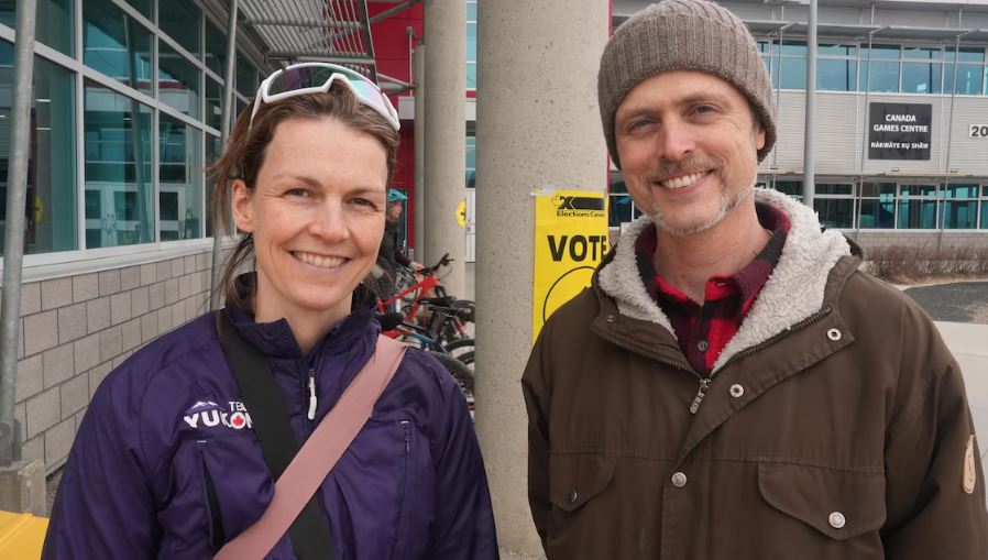 Une femme et un homme à la sortie d'un bureau de vote de Whitehorse, au Yukon, le 28 avril 2025.