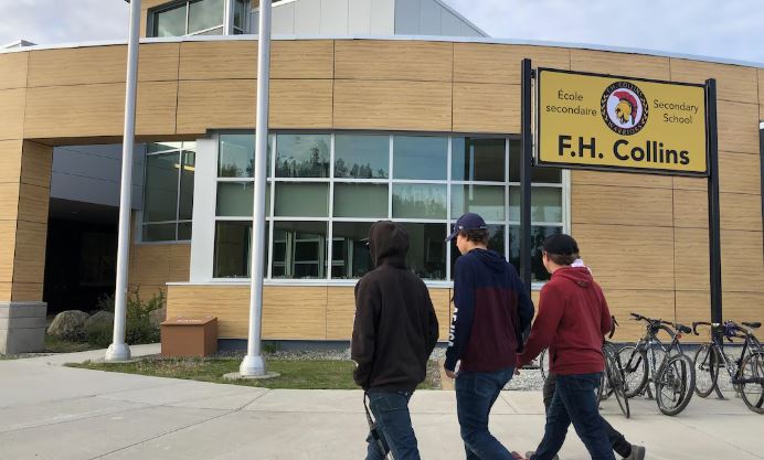 Des élèves marchent devant la façade de l'école.