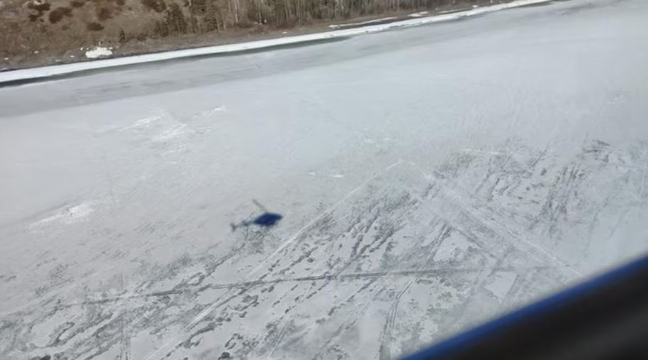 L'ombre d'un hélicoptère sur la glace d'un fleuve gelé.