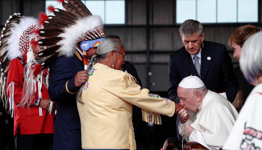 Le pape embrasse la main d'une femme.