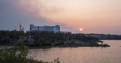 De la fumée surplombe l'hôpital territorial Stanton de Yellowknife, le 15 août 2023.