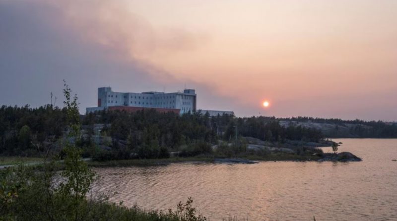 De la fumée surplombe l'hôpital territorial Stanton de Yellowknife, le 15 août 2023.