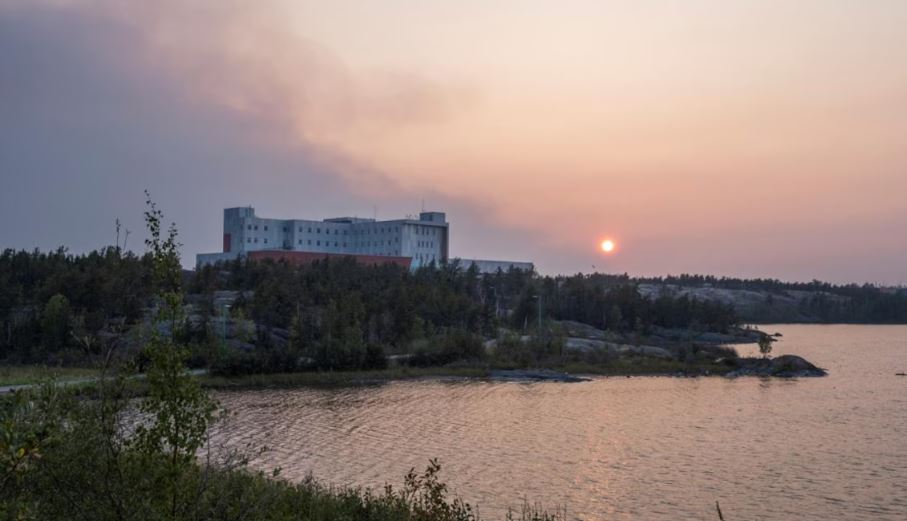 De la fumée surplombe l'hôpital territorial Stanton de Yellowknife, le 15 août 2023.